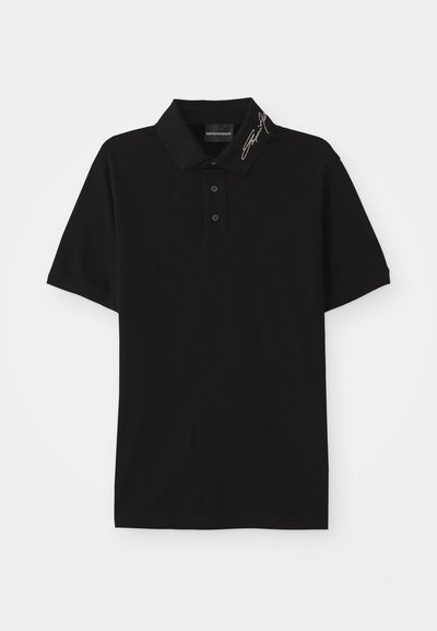 Svart polotröja i mjukt material, med krage, placket med tre knappar, korta ärmar och signerad detalj på kragen.