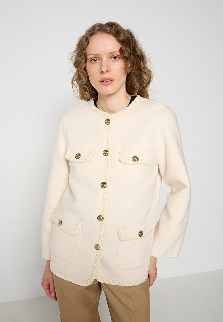Cremefarbener Cardigan mit strukturierter Oberfläche, ausgestattet mit goldfarbenen Knöpfen, zwei Vordertaschen und geflochtenem Besatz entlang der Kanten.