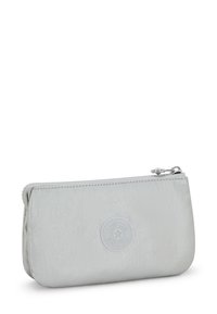 Zippered pouch in light gray nylon with a soft texture, rounded shape, and a circular logo accent on the front.