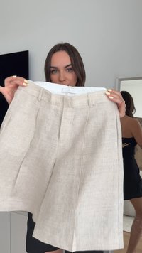 Beige linen shorts with a flat front, two side pockets, and a tailored fit. The fabric has a textured weave, enhancing its casual appearance.