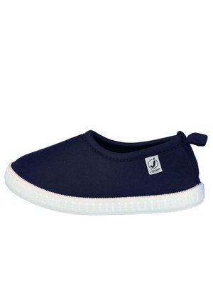 Zapato azul marino tipo slip-on con suela de goma blanca y una pequeña etiqueta de tela de la marca en el lateral, diseñado para uso casual.