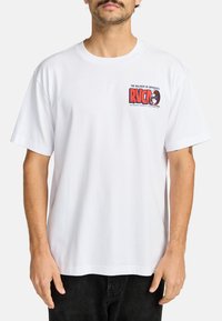 Camiseta de algodón blanca con un colorido estampado gráfico en el pecho que incluye el texto "RVCA". Diseño de mangas cortas y ajuste relajado.