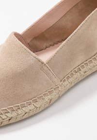 Espadrille en suédine beige avec un bout rond, des détails cousus et une semelle en jute tressé. Doublure intérieure lisse de couleur claire.