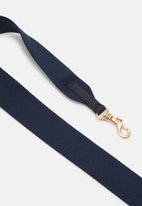 Sangle en tissu bleu marine avec un clip en métal doré et des accents noirs, design plat avec une surface texturée, adaptée pour fixer les objets en toute sécurité.