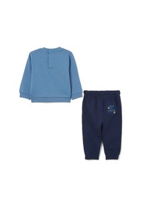 Chemise à manches longues bleu clair avec un détail de boutonnage à l'arrière, associée à un jogging bleu marine avec une poche décorative et le texte "Into the Forest".