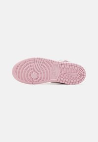 Rozā gumijas sporta apavu zole ar apaļu protektora rakstu, teksturētām saķeres daļām un Nike logo detaļām. Plakans dizains, kas piemērots ikdienas valkāšanai.
