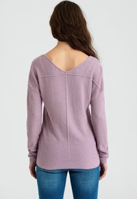 Fialkový pletený svetr se širokým výstřihem do V, dlouhými rukávy a žebrovanými manžetami. Texturovaná látka s volným střihem a rovný zadní šev.