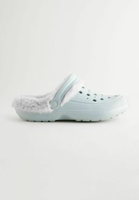 Hellblaue Clogs mit flauschigem grauem Futter, Belüftungslöchern und einem geformten Design. Langlebiges Material und rutschfeste Sohle.