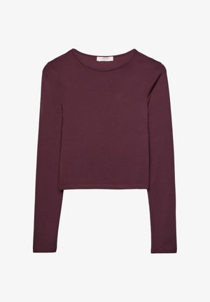Bordo dugih rukava crop top od mekanog materijala. Ima okrugli izrez i prošivene rubove, s oblikovanim siluetom.