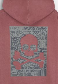 Sudadera roja con capucha que presenta un diseño gráfico con una calavera y tibias cruzadas, rodeado de varios textos en negro y gris en la parte posterior.