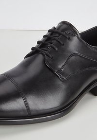 Scarpa da uomo in pelle nera, con punta arrotondata, design con lacci, dettagli di cucitura discreti e una texture liscia. Presenta un tacco basso.
