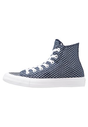 Baskets montantes avec un motif tissé bleu marine et blanc, lacets blancs et semelle en caoutchouc blanche, présentées en profil sur un fond blanc.