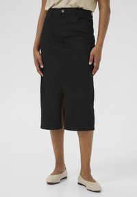 Jupe en denim noir, coupe crayon, avec une fente à l'avant, mi-longue, présentant un design simple, des passants de ceinture et une fermeture à un seul bouton.