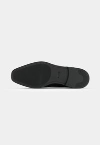 Suela de zapato de cuero negro con un diseño liso y plano. Presenta una marca sutil y un patrón de agarre texturizado para mayor tracción.