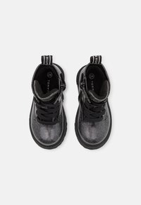 Botas negras hasta el tobillo con una textura brillante y brillante, que cuentan con cordones, una cremallera y una lengüeta en la parte posterior para facilitar su uso. Talla 24.
