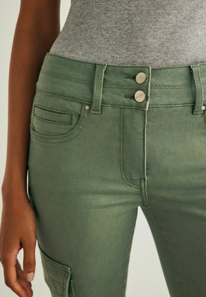 Gröna denim cargo-byxor med hög midja, som har två framskjutna knappar, sidofickor och en slät, något texturerad yta.