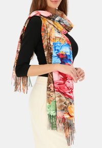 Chusta w kwiaty w żywych kolorach, w tym niebieskim, różowym i pomarańczowym; wykonana z miękkiego materiału z frędzlami na krawędziach.