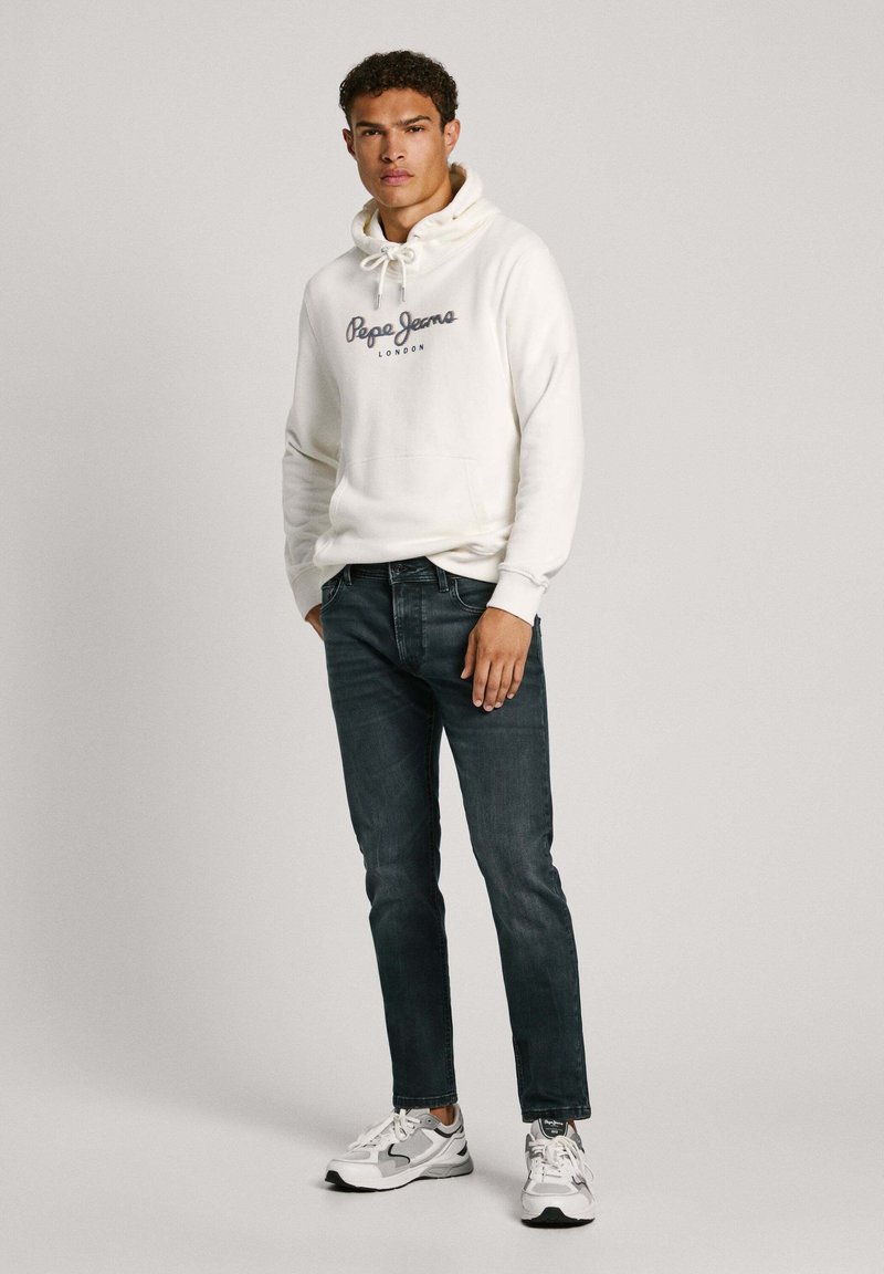 Weißer Kapuzenpullover mit "Pepe Jeans London"-Logo, kombiniert mit dunkelblauen Jeans und grauen Sneakers. Glatter Stoff, lässiger Schnitt.