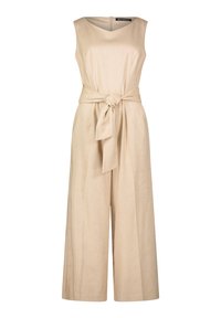 Combinaison en lin beige avec un design sans manches, coupe large, détail de ceinture à la taille et décolleté en V. Elle présente une fermeture éclair discrète à l'arrière.