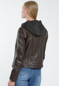 Brun läderjacka med en mörkgrå tygkappa. Har figursydda ärmar och en paneldesign med synlig sömnad.