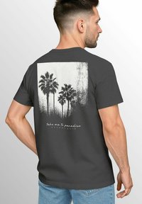 Dunkelgraues T-Shirt mit einem weißen Grafikdruck von Palmen und dem Text "Bring mich ins Paradies" in einer stilisierten Schriftart. Lässiger Baumwollstoff.