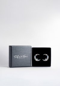 Silverfärgade ringörhängen prydda med flerfärgade blommor, presenterade i en svart texturerad smyckesask med vit logotyp.