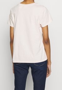 Ljust rosa bomulls-t-shirt med korta ärmar, rund halsringning och rak nederkant. Enkelt mönster utan synliga mönster eller detaljer.