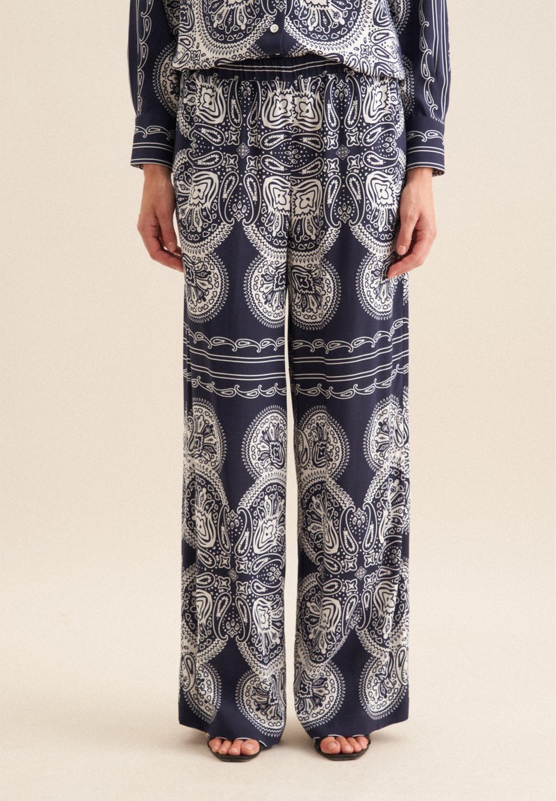 Navy-gestreepte broek met wijde pijpen en een wit paisley ontwerp. Lichtgewicht stof, elastische tailleband en zijzakken. Casual en vloeiende pasvorm.