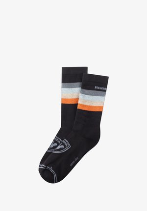 Sorte strømper med ribbet tekstur, der har vandrette striber i lys blå, beige og orange. Inkluderer et gråt logo på siden.