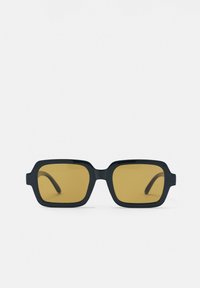 Lunettes de soleil rectangulaires noires avec des montures épaisses et des verres teintés ambrés, vues de face sur fond blanc.
