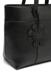 Czarna skórzana torebka o teksturowanym wykończeniu, z akcentem w postaci kwiatowego wycięcia w tym samym kolorze oraz dwoma mocnymi uchwytami.