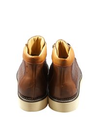 Stivaletti alla caviglia in pelle marrone con design testurizzato, dettagli in marrone chiaro e suola in gomma color crema. Caratterizzati da una forma elegante e dettagli con cuciture.