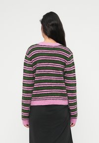 Πουλόβερ με ρίγες σε πράσινο, ροζ και μαύρο χρώμα. Κατασκευασμένο από αφράτο υλικό με ριμπ μανσέτες και στρογγυλή λαιμόκοψη.