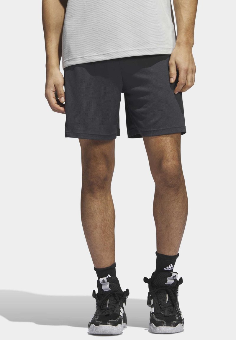 Shorts de sport gris foncé avec une texture lisse, dotés d'une taille élastique et d'une longueur mi-cuisse, associés à des chaussures de sport noires.