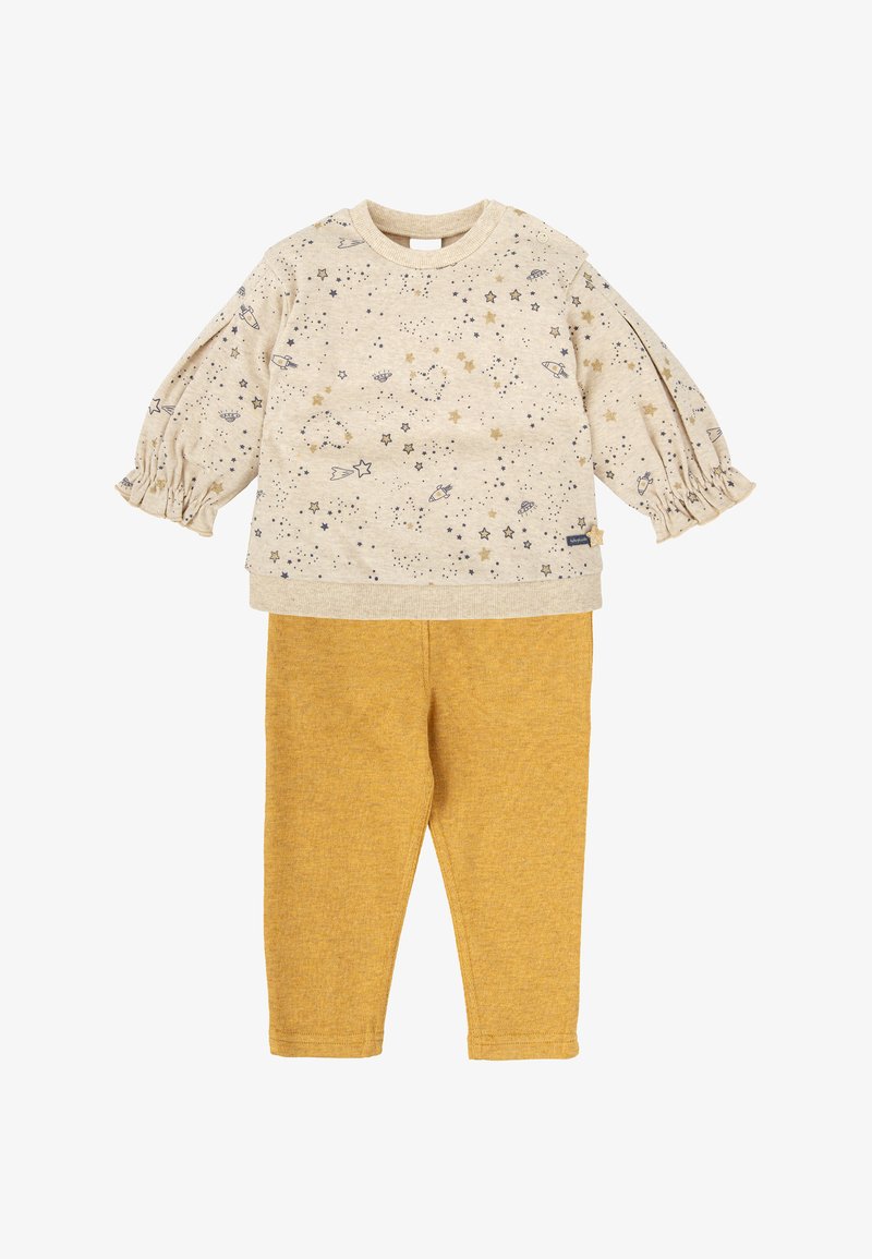 Camisa de manga larga beige con estampado de estrellas y planetas, combinada con pantalones amarillos mostaza. Tela texturizada con mangas fruncidas y cuello redondo.