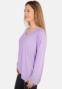 Langan Ärmel in sanftem Lila mit V-Ausschnitt, aus weichem Material gefertigt. Verfügt über eine lockere Passform und einen leicht abgerundeten Saum für lässige Kleidung.