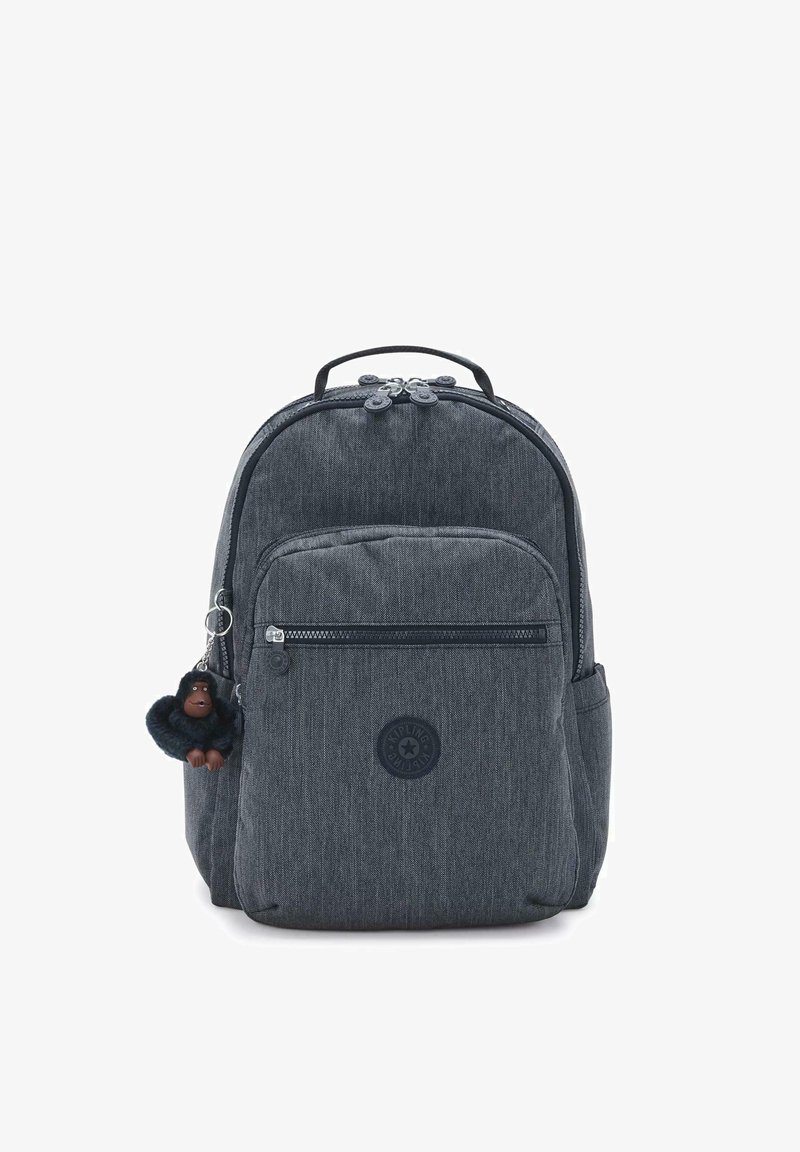 Szary plecak z materiału o teksturowanym wykończeniu, z kieszeniami zapinanymi na suwak, okrągłym logo i przywieszką w kształcie pluszowej małpki.