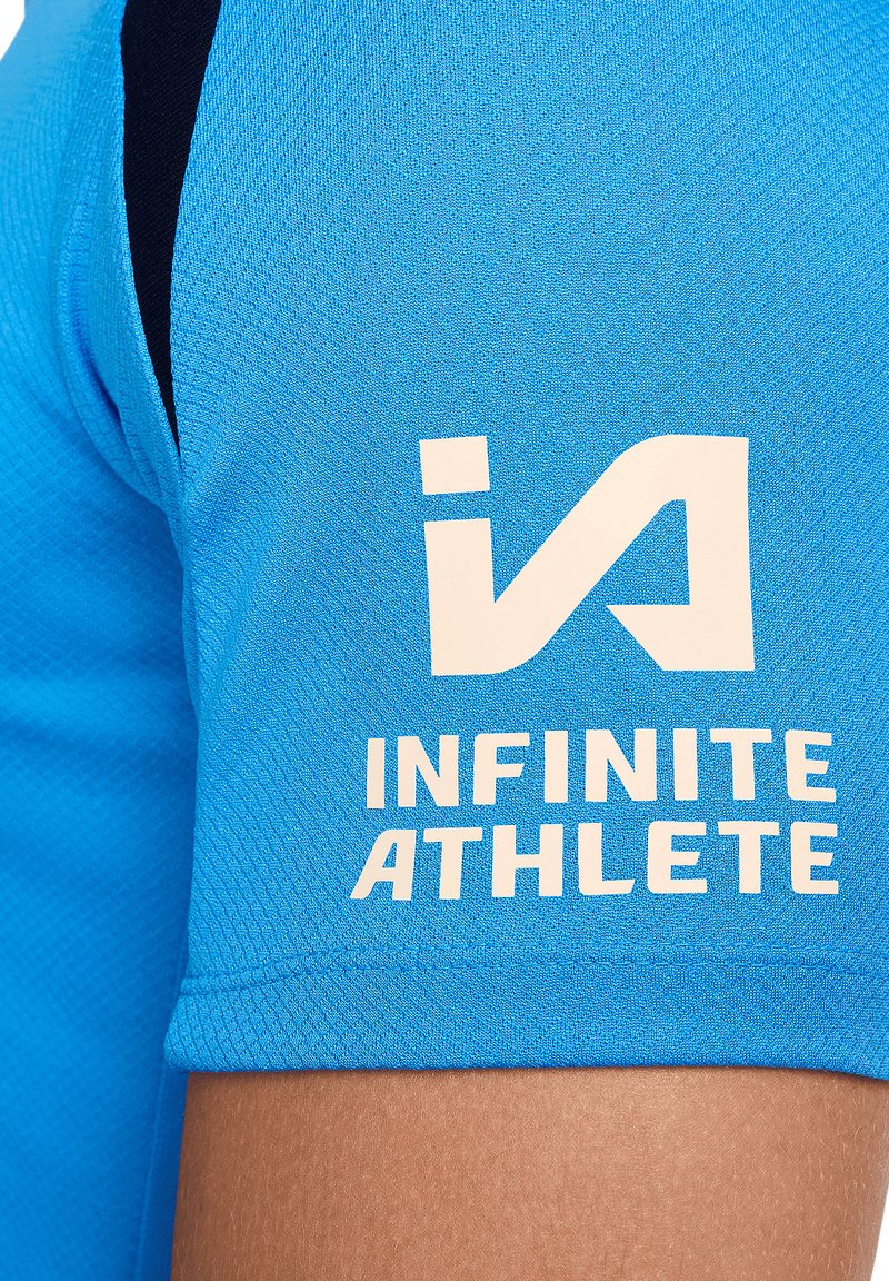 T-shirt de sport bleu clair avec un tissu texturé. Présente des accents noirs sur l'épaule et un texte blanc : "INFINITE ATHLETE" accompagné d'un logo.