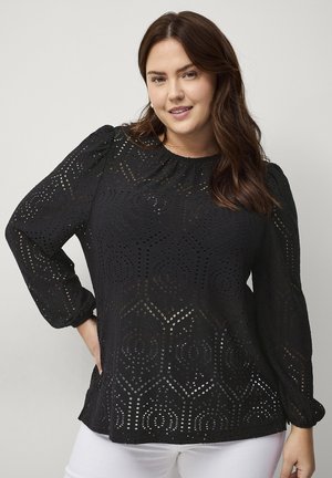 Zwarte blouse met lange, opbollende mouwen, voorzien van een geometrisch uitgesneden patroon en een ronde halslijn, gemaakt van textuurstof.