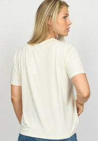 Korte ærmer beige t-shirt i blødt materiale med en rund halsudskæring og en afslappet pasform, der har en glat overflade og minimalistisk design.