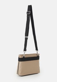 Borsa tote in tessuto beige con una band nera, forma rettangolare, tracolla nera regolabile, accessori in argento e texture liscia.