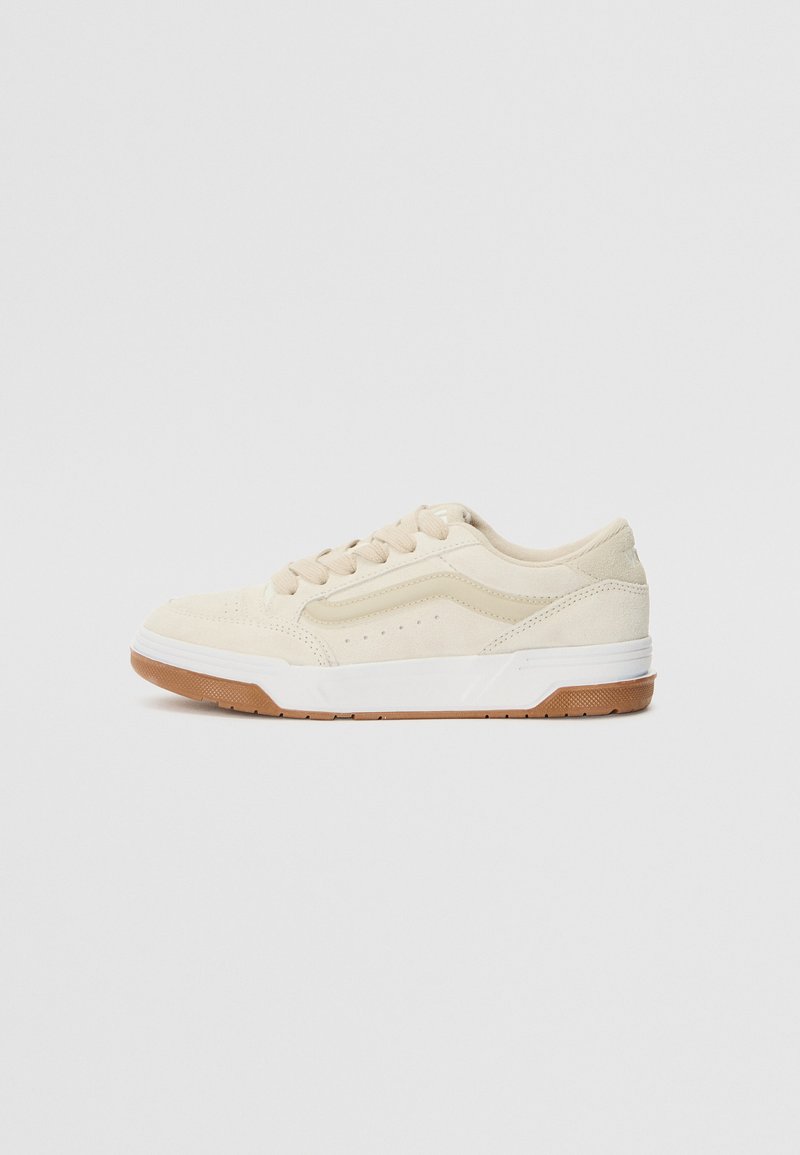 Beige suede sneakers with white soles and gum rubber outsole. Features lace-up design and perforated accents on the side.