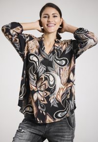 Schwarze Bluse mit einem auffälligen, bunten Blumen- und Paisleymuster. Hergestellt aus leichtem Stoff mit einer entspannten Silhouette und V-Ausschnitt.