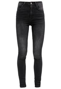 Jeans ajustados de tiro alto en negro, confeccionados en denim, con cremallera frontal, costuras en tono y dos bolsillos, presentando una textura suave y ligeramente deslavada.