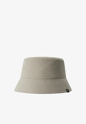 Cappello a secchiello beige realizzato in tessuto con una consistenza liscia. Presenta una visiera ampia e dettagli cuciti lungo il bordo. Piccolo logo sul lato.
