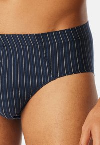 Caleçons de bain rayés bleu marine et blancs en tissu doux et extensible. Caractérisés par une taille large et une coupe ajustée, offrant confort et soutien.