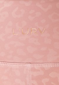 Růžová tkanina s jemným potiskem leopardí kožešiny. Obsahuje zlatě ražený text "L'URV" a viditelné detaily šití.