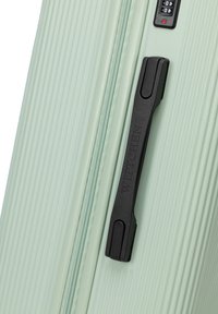 Light green suitcase with a textured herringbone pattern, black handle, and combination lock. Zipper closure along the edge.