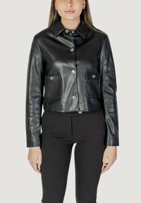 Giacca cropped in pelle nera con colletto, chiusura frontale a bottoni e due tasche sul petto con accenti metallici.