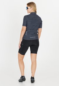 Herrcykelskjorta i mörkgrått med ett subtilt randigt mönster, korta ärmar och bakfickor; kombinerad med svarta cykelshorts.